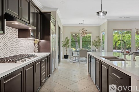 A modern kitchen with dark brown cabinets and a white countertop.