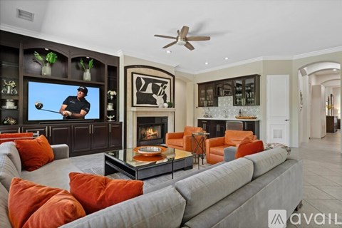 A living room with a grey couch and a television showing a golf player.