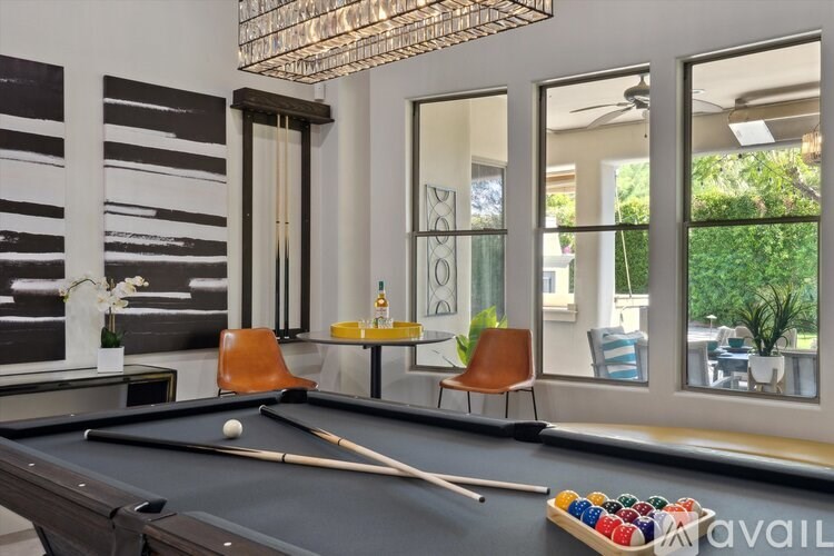 A pool table is set up in a room with a chair and a rack of balls.