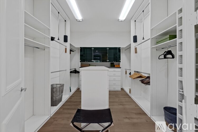 A white chair is in the middle of a room with white walls and wooden floors.