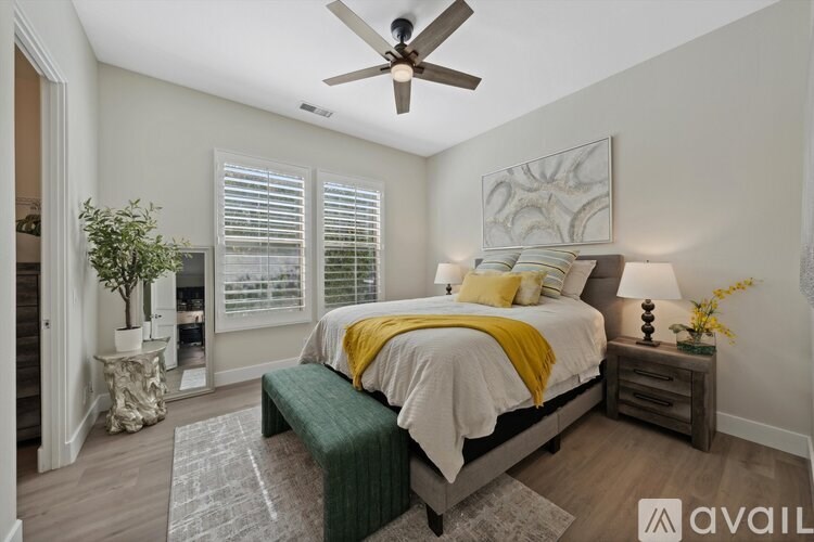 A bedroom with a bed, a bench, and a ceiling fan.