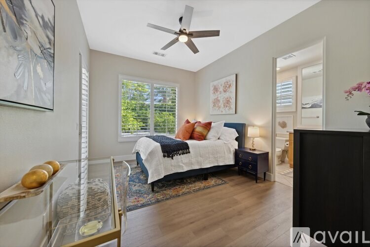 A bedroom with a bed, a ceiling fan, and a window.