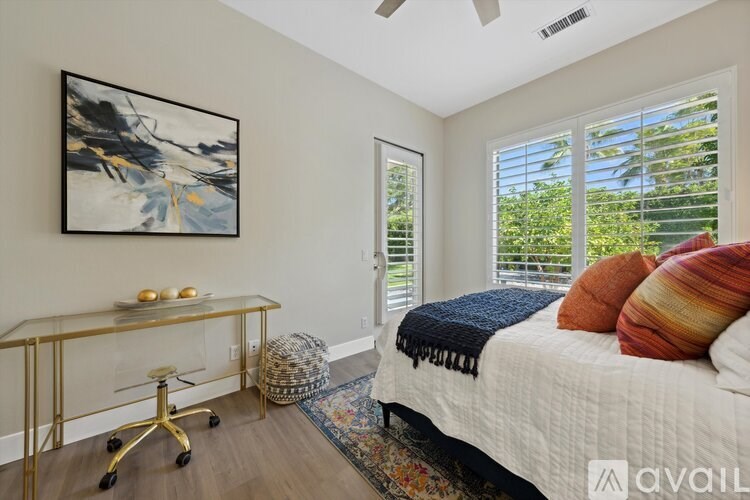 A bedroom with a bed, a desk, and a painting on the wall.
