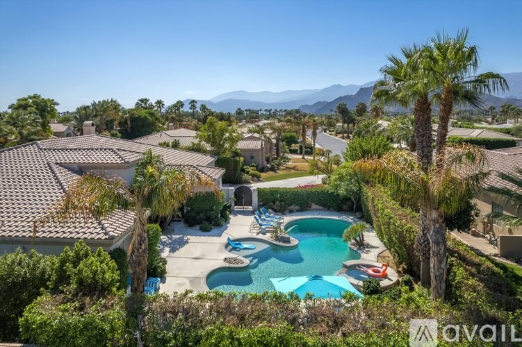 A large house with a pool and palm trees in the foreground.