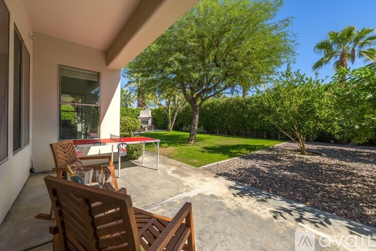 A patio with a table and chairs overlooks a garden.