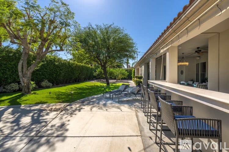 A sunny day at the outdoor patio of a building with chairs and a table.