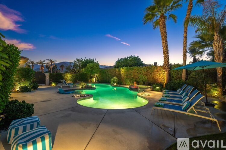 A pool surrounded by palm trees and lounge chairs.