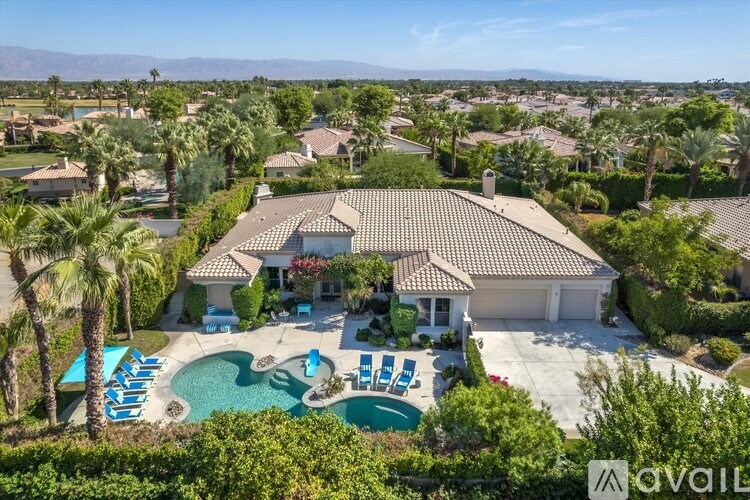 A large house with a pool and palm trees in the front yard.