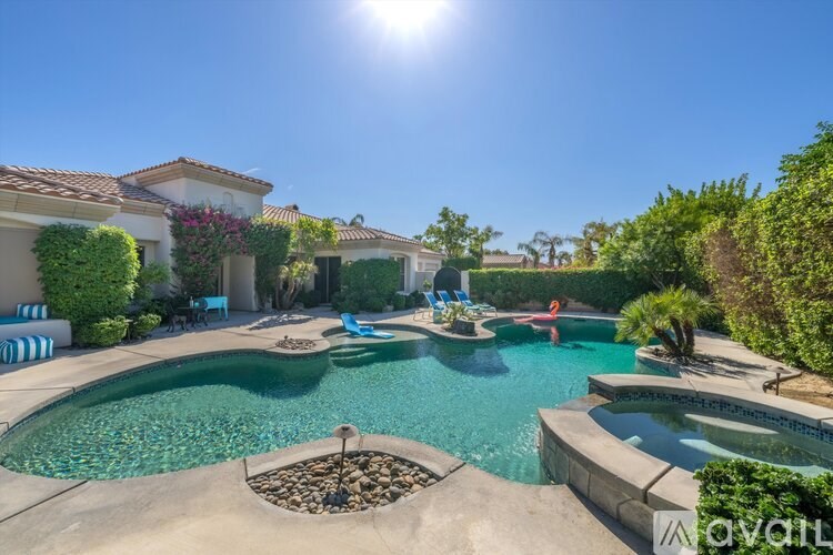 A sunny day at a pool with a house in the background.