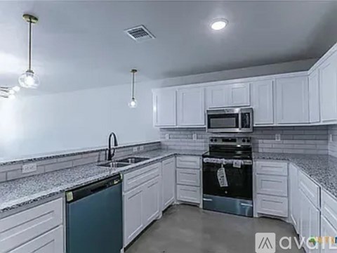 A kitchen with white cabinets and a black dishwasher.