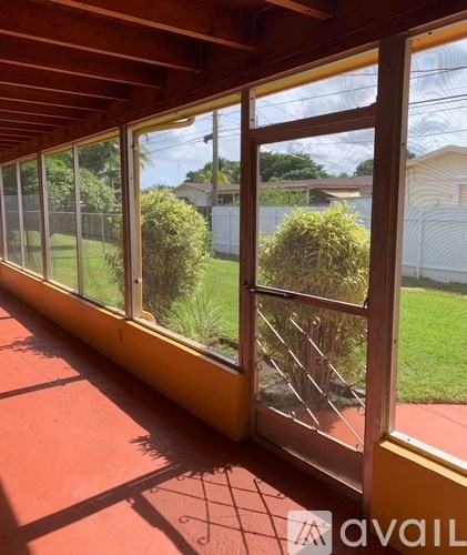 A sunny day with a view of a green lawn and a house through a window.