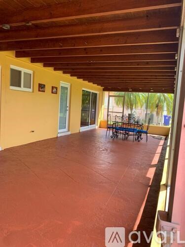 A patio with a table and chairs is covered with a red floor.