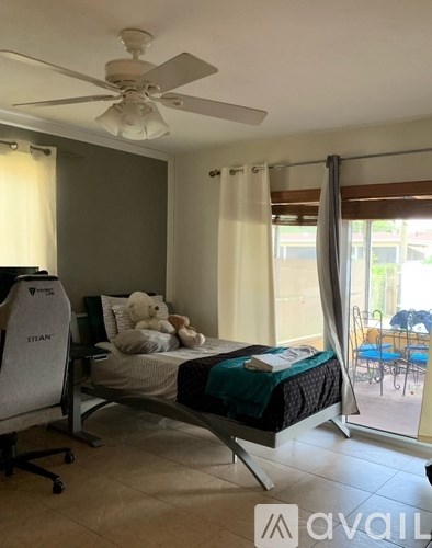 A room with a bed, a chair, and a ceiling fan.