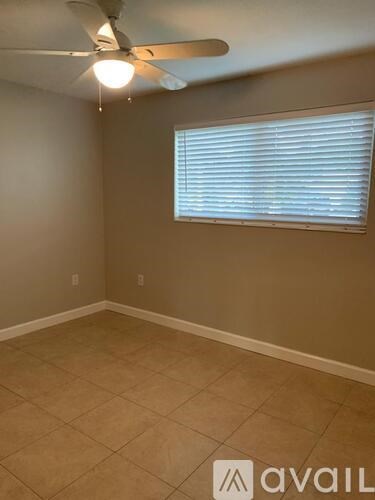 A room with a ceiling fan and a window with blinds.