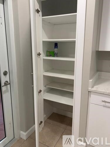 A white pantry with an open door.