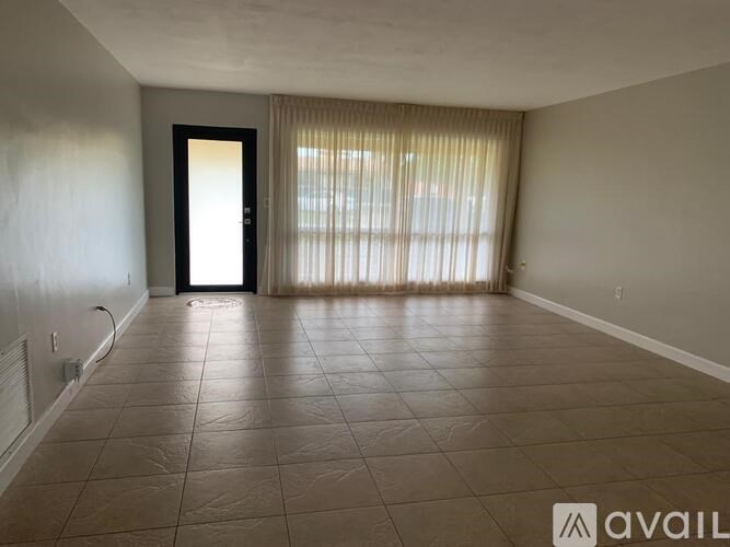 A spacious room with a door and a window with curtains.