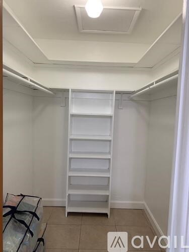 A white closet with a shelf and a bag on the floor.