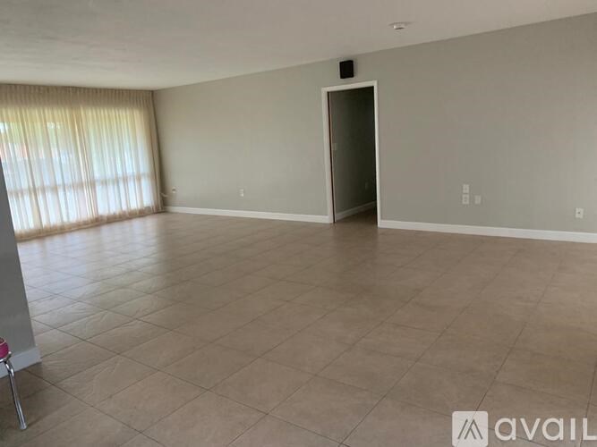 A spacious room with a tiled floor and a large window with curtains.