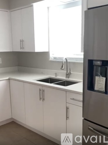 A kitchen with white cabinets and a stainless steel refrigerator.