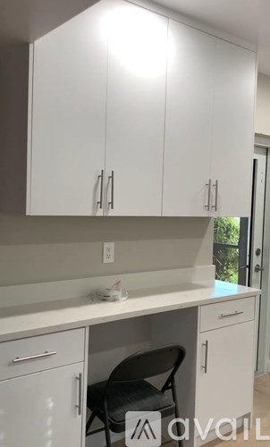 A kitchen with white cabinets and a black chair.