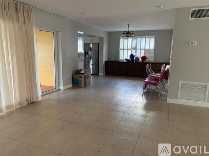 A spacious living room with a large window, a sofa, and a dining table.