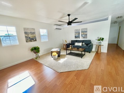 A living room with a couch, a rug, a ceiling fan, and a window.