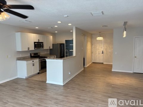 A spacious kitchen with white cabinets and a darker floor.