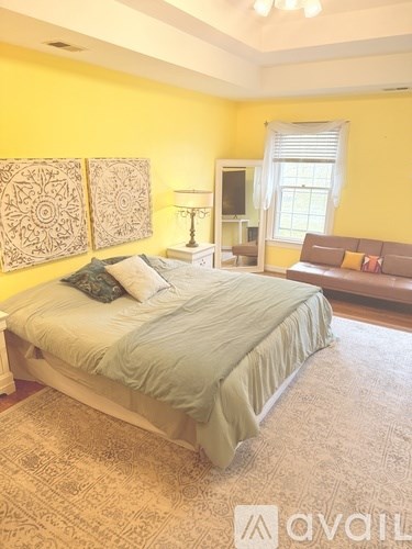 A bedroom with a bed, a couch, and a lamp.