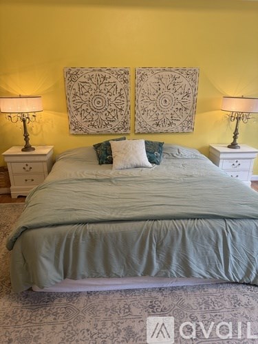 A bedroom with a bed, two lamps, and two wall hangings.