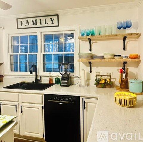A kitchen with a black dishwasher and a window above the sink.