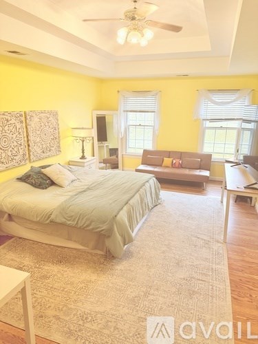 A bedroom with a bed, a couch, and a ceiling fan.