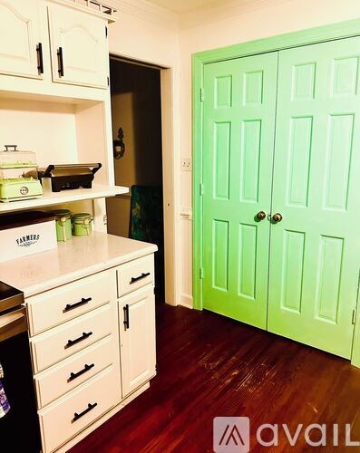 A kitchen with a green door and white cabinets.
