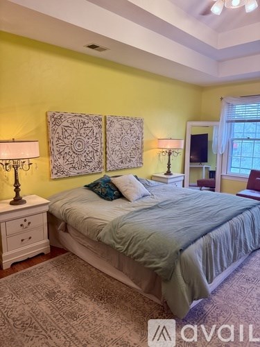 A bedroom with a bed, two lamps, and two wall hangings.