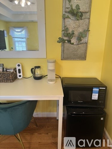 A white desk with a green chair and a black printer.