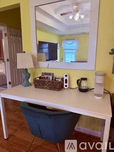 A white desk with a blue chair and a mirror above it.