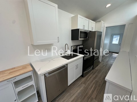 A kitchen with white cabinets and a wooden countertop is available for rent.