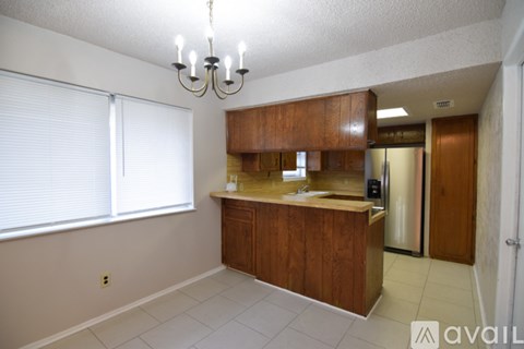 A kitchen with wooden cabinets and a chandelier.