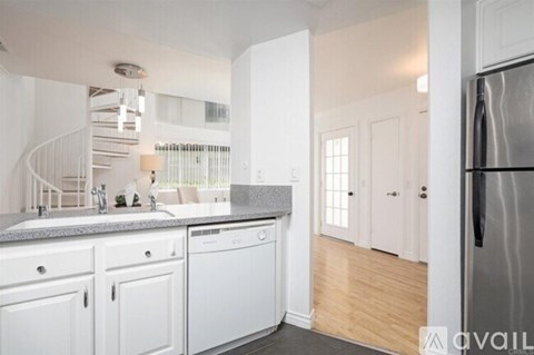A kitchen with white cabinets and a stainless steel refrigerator.