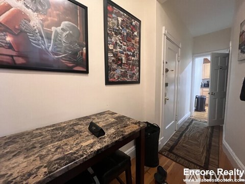 A hallway with a table and two pictures on the wall.