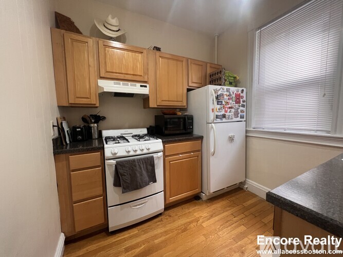 A kitchen with wooden cabinets and a white stove top oven.
