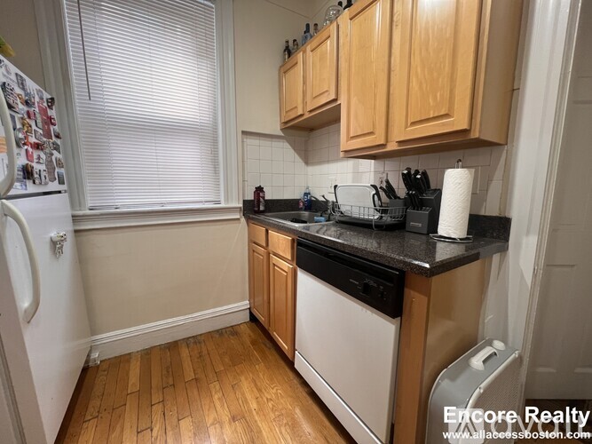 A kitchen with wooden cabinets and black countertops.