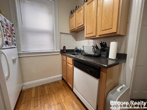 A kitchen with wooden cabinets and black countertops.
