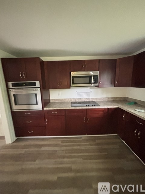 A kitchen with brown cabinets and a stainless steel oven.