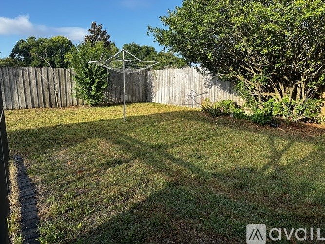 A backyard with a fence, a tree, and a swing set.