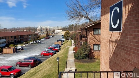 A parking lot with cars parked in it and a building with a C on it.