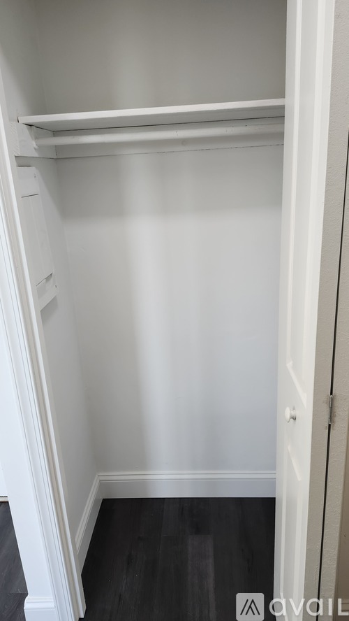 A white closet with a shelf and a door.