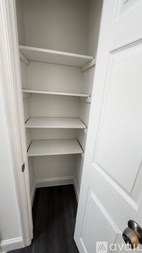 A white door with a handle and a white shelf.