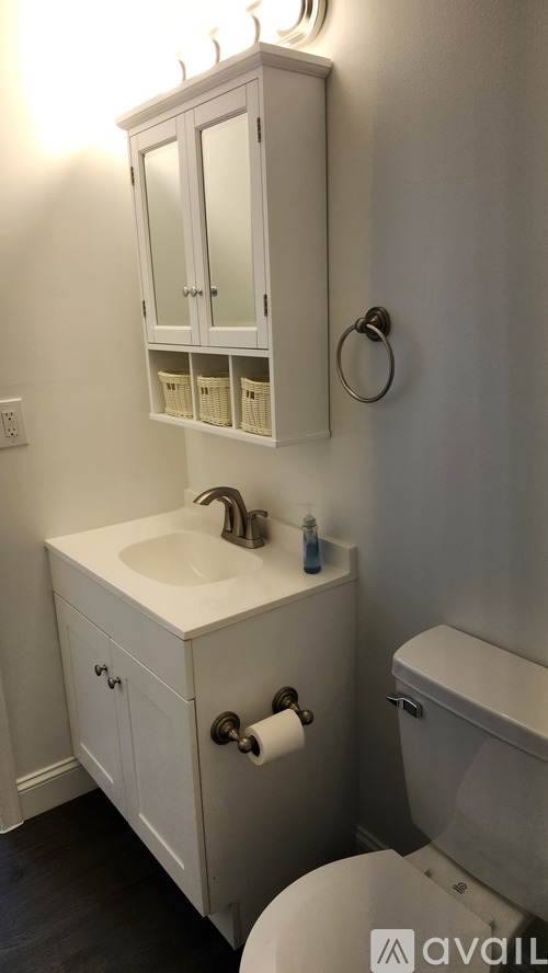 A white bathroom with a toilet, sink, and medicine cabinet.
