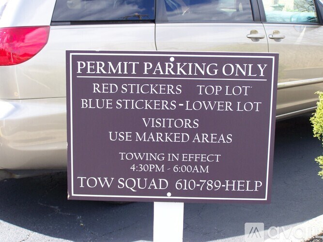 A parking sign indicates that only vehicles with red stickers can park in the top lot, while those with blue stickers can park in the lower lot.