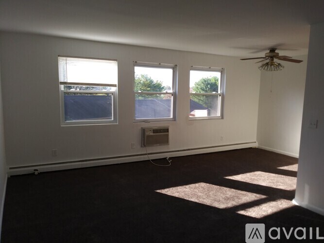 A room with a ceiling fan and three windows.